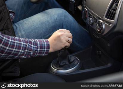 Closeup shot of young man shifting manual gearbox in car