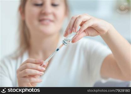 Closeup shot of young medical worker filling syringe with drug