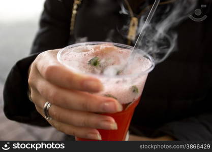 Closeup shot of young woman holding plastic cup with vaporizing fruit tea