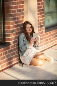 Closeup shot of young woman sitting on street and using tablet