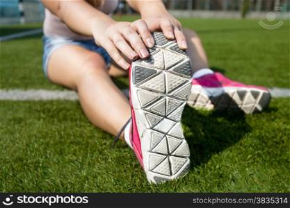 Closeup shot of young woman stretching on grass before jogging