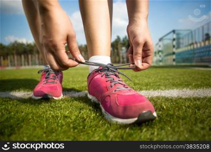 Closeup shot of young woman tying shoe laces before running