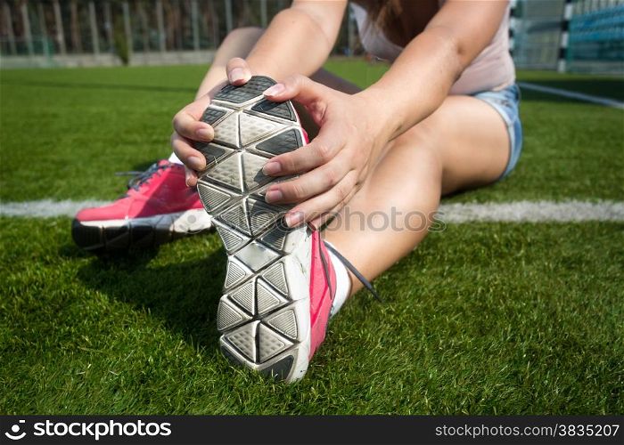 Closeup shot of young woman warming up on grass before running