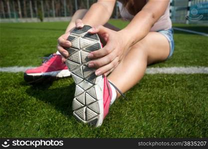 Closeup shot of young woman warming up on grass before running