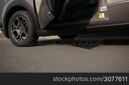 Closeup slender woman&acute;s legs in orange high heel shoes getting out of luxury car. Beautiful slim female legs in high heels exiting automobile from driver&acute;s seat. Slow motion.