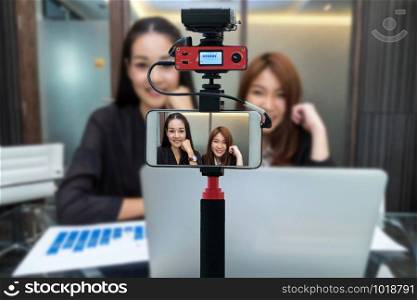 Closeup smart mobile phone taking Live of Two Asian young Businesswoman, Camera for photographer or Video and Live Streaming concept