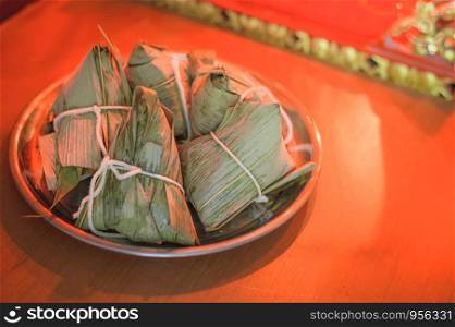 Closeup Sticky rice dumpling or Zongzi on stainless steel tray in front of Chinese spirit's house during Dragon Boat Festival. Pay respect to ancestor.