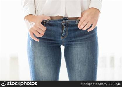 Closeup studio photo of sexy woman with perfect body wearing blue jeans