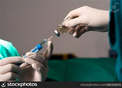 Closeup surgeon hand with protective glove fills syringe from vial in preparation for surgical procedure at sterile operation room. Doctor prepare syringe to inject anesthesia into patient.