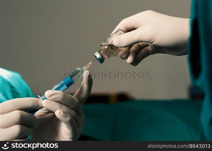 Closeup surgeon hand with protective glove fills syringe from vial in preparation for surgical procedure at sterile operation room. Doctor prepare syringe to inject anesthesia into patient.. Closeup surgeon fill syringe for surgical procedure at sterile operation room.
