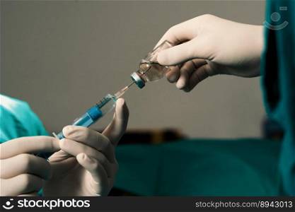 Closeup surgeon hand with protective glove fills syringe from vial in preparation for surgical procedure at sterile operation room. Doctor prepare syringe to inject anesthesia into patient.. Closeup surgeon fill syringe for surgical procedure at sterile operation room.