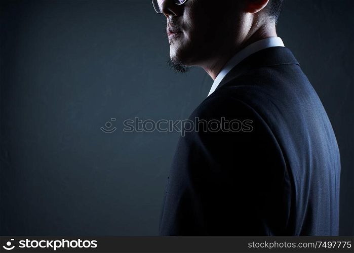 Closeup three quarter rear view of businessman with black background