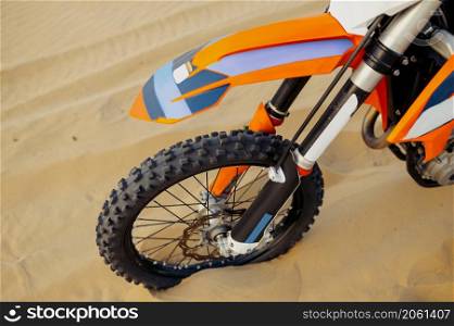 Closeup tire of sport motorcycle with soft-focus. Motocross bike wheel over sand top view. Closeup tire of sport motorcycle with soft-focus