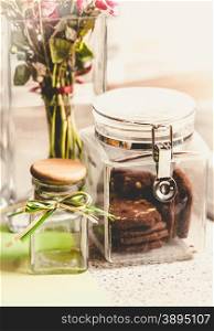 Closeup toned photo of chocolate cookies in glass jar on kitchen table