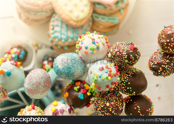 Closeup toned photo of colorful cake pops and cookies with icing