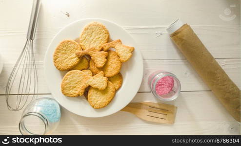 Closeup toned photo of kitchen utensils, ingredients and cookies lying on white wooden desk