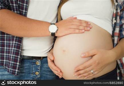 Closeup toned photo of young man touching pregnant wife&rsquo;s belly