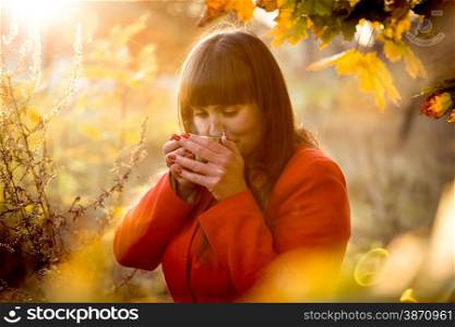 Closeup toned portrait of elegant cute woman drinking tea at cold autumn day at park