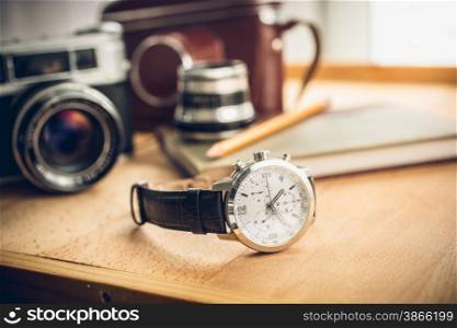 Closeup toned shot of male watches lying on table against photography retro set