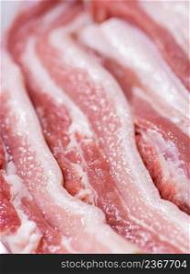 Closeup top view pieces fresh raw meat of pork belly with white fat and red pink meat. Closeup pieces of raw pork belly