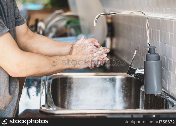 Closeup-up Asian man hand washing with faucet water in kitchen at home, Health care of Covid-19 pandemic , cleaning and carefree concept