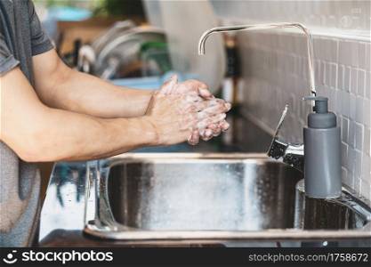 Closeup-up Asian man hand washing with faucet water in kitchen at home, Health care of Covid-19 pandemic , cleaning and carefree concept