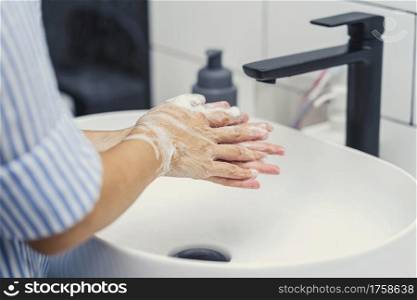 Closeup-up Asian woman hand washing with faucet water in Bathroom at home, Health care of Covid-19 pandemic , cleaning and carefree concept