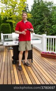 Closeup vertical photo of mature man pouring beer into glass with BBQ grill and open cedar patio with seasonal trees in full bloom in background