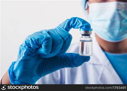 Closeup vial of covid-19 vaccine in hand of professional scientist or doctor in laboratory for treatment with mask gloves and lab coat on white background. Health business and industry concept.