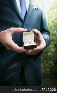 Closeup view elegant groom holding open box with wedding rings