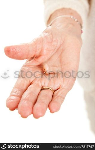 Closeup view of a hearing aid in the hand of a senior woman.