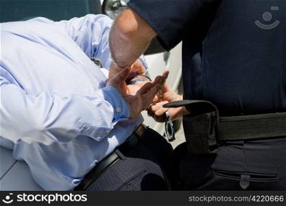 Closeup view of a police officer handcuffing a businessman.