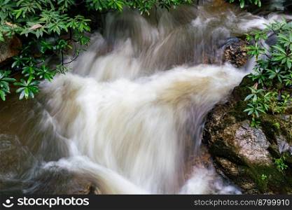 Closeup view of clear natural mountain stream water flowing over the boulders in the rainforest at Chae Son National Park in Thailand.