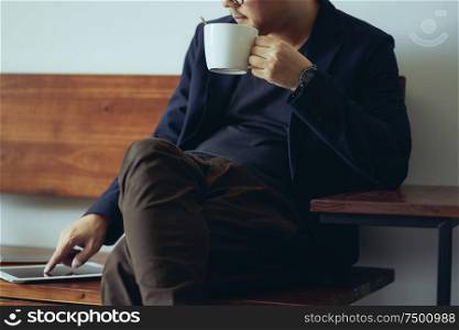 Closeup view of relaxing businessman using digital pad and drink the coffee .