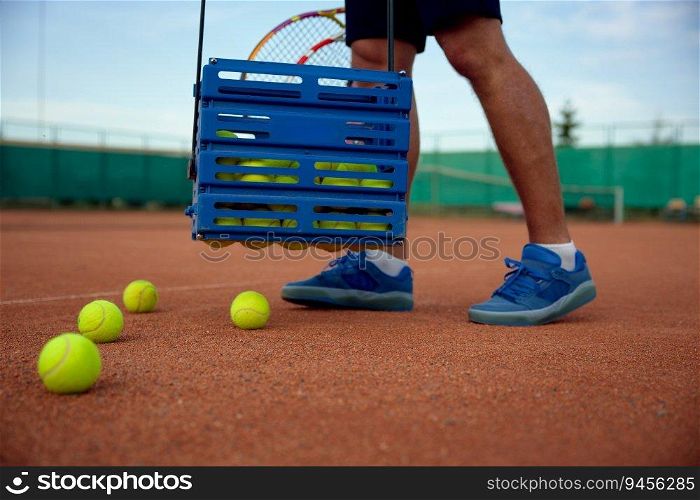 Closeup view of tennis player picking up scattered balls on field after game training. Professional occupation or hobby recreation concept. Closeup view of tennis player picking up scattered balls on field