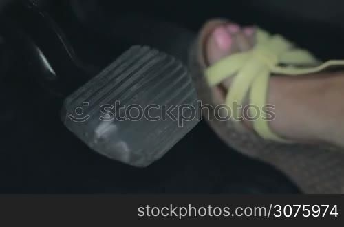 Closeup view of woman&acute;s foot depressing the gas pedal of car and pressing the brake pedal for emergency stop.
