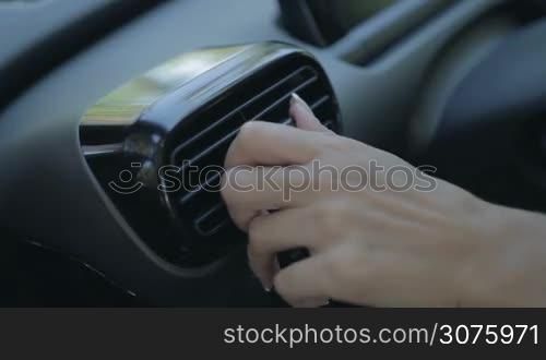 Closeup view of woman hand using automobile air conditioning system