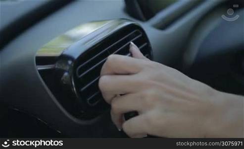 Closeup view of woman hand using automobile air conditioning system