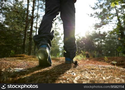 Closeup view on male hiker legs walking along forest paths. Healthy lifestyle in nature. Closeup view on male hiker legs walking along forest paths