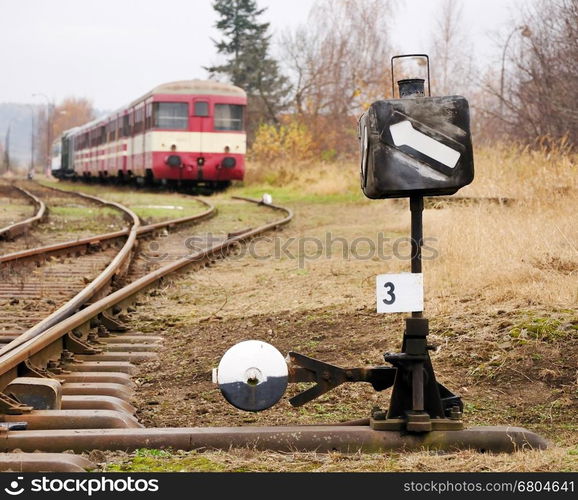 Closeup view to the railroad switch with old passenger train in back.