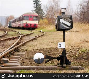 Closeup view to the railroad switch with old passenger train in back.