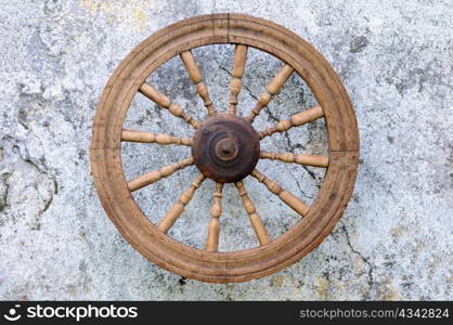 Closeup vintage spinning wheel against shabby wall background
