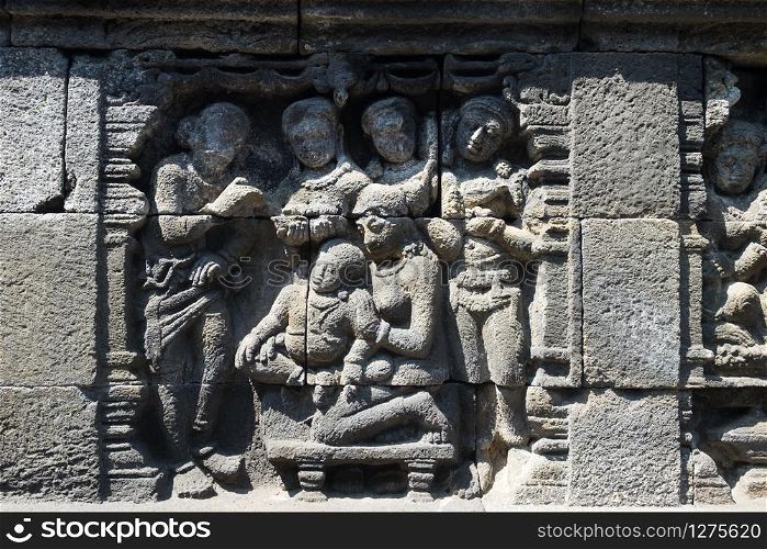 Closeup wall ornamented with bas-reliefs religion scene. Highly detailed stone carving. Borobudur Buddhist temple, Magelang, Indonesia