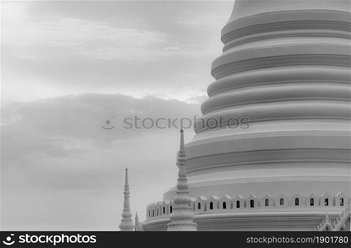 Closeup white pagoda in Thai temple. Classical architecture. Attraction art and ancient architecture in Thailand. Buddhist temple with white sky and gray cloud. Religion architecture. Peaceful concept