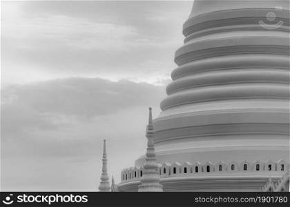Closeup white pagoda in Thai temple. Classical architecture. Attraction art and ancient architecture in Thailand. Buddhist temple with white sky and gray cloud. Religion architecture. Peaceful concept