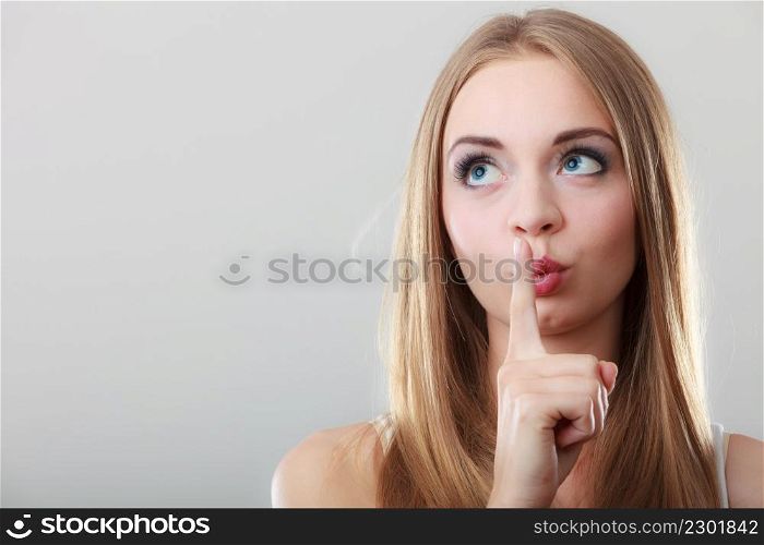 Closeup woman asking for silence or secrecy with finger on lips hush hand gesture, on gray background
