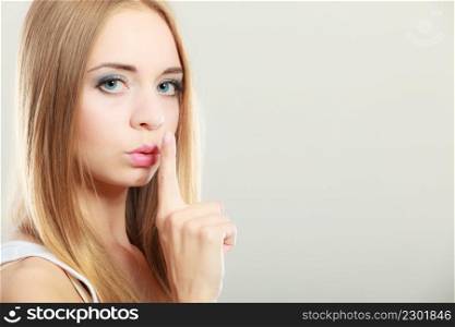 Closeup woman asking for silence or secrecy with finger on lips hush hand gesture, on gray background