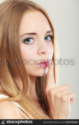 Closeup woman asking for silence or secrecy with finger on lips hush hand gesture, on gray background