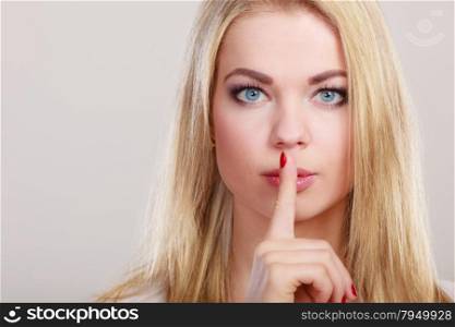 Closeup woman asking for silence or secrecy with finger on lips hush hand gesture. On gray background