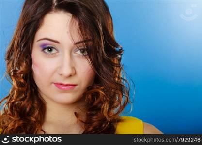 Closeup woman face, girl with long brown curly hair colorful makeup portrait on blue